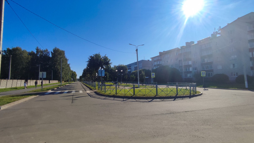 Широкий перекрёсток с островком безопасности, ограждением и знаками пешеходного перехода у жилых домов