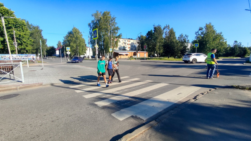 Трое подростков переходят дорогу по «зебре» на большом перекрёстке