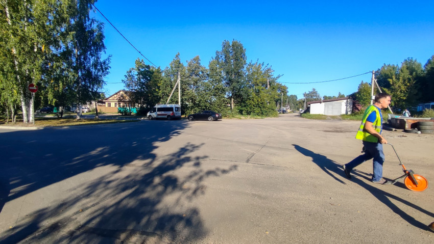 Широкий участок дороги у перекрёстка с припаркованными машинами и знаком «кирпич»