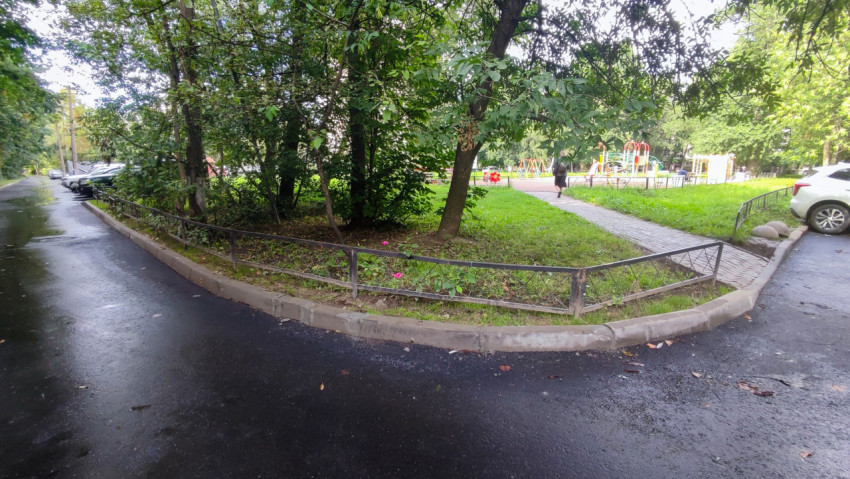 Дворовый проезд с новым асфальтом, бордюром и газоном рядом с детской площадкой
