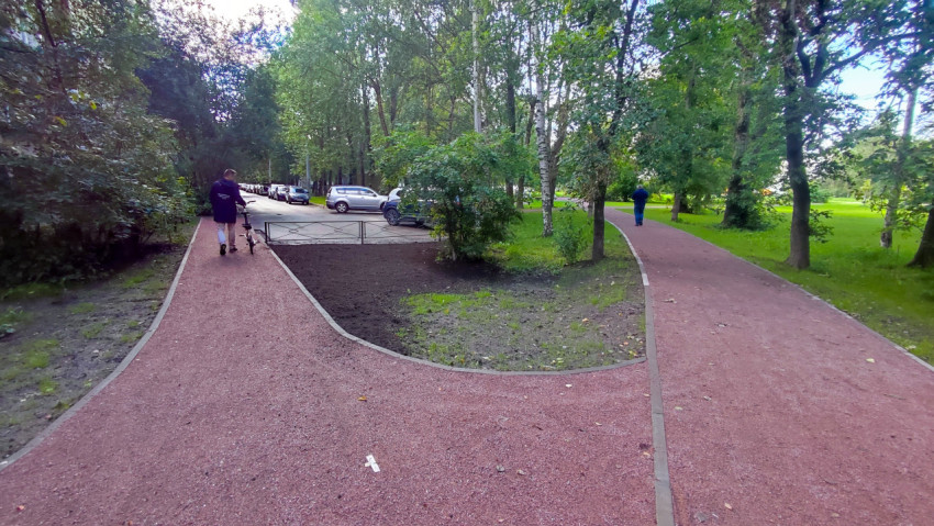 Разветвление пешеходных дорожек с красным покрытием в городском парке среди деревьев