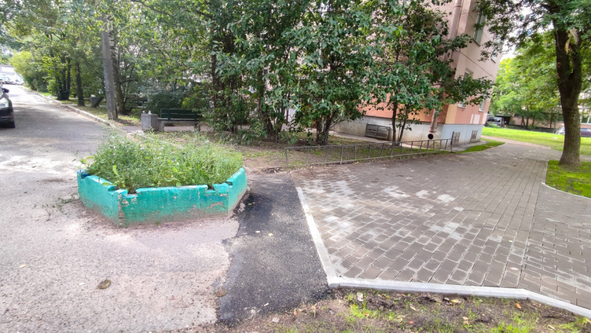 Двор с плиткой, клумбой и аккуратными дорожками возле подъезда