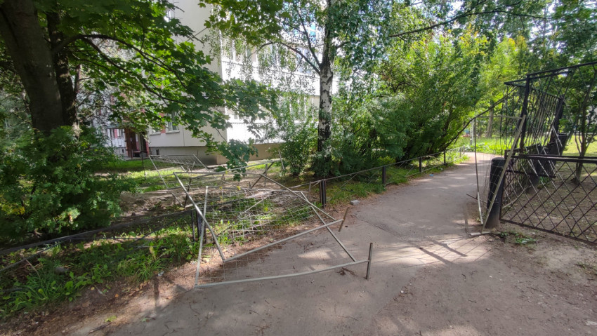 Упавшие секции временного забора перекрывают проход по тротуару у жилого дома