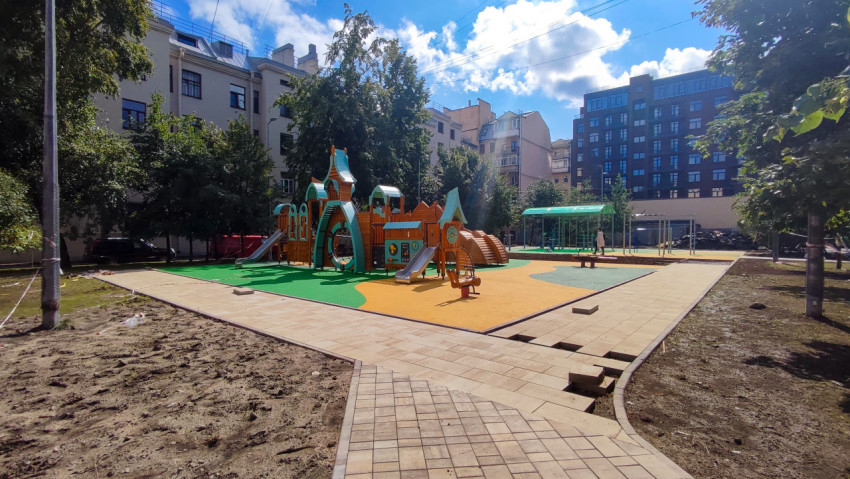 Детская площадка с деревянным игровым комплексом и резиновым покрытием во дворе