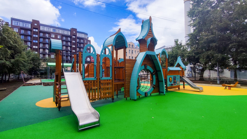 Игровая площадка с деревянным комплексом, второй горкой и цветными зонами покрытия