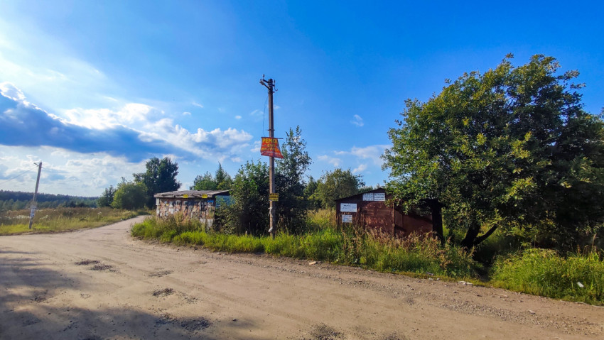 Поворот грунтовой дороги между гаражами и зарослями травы