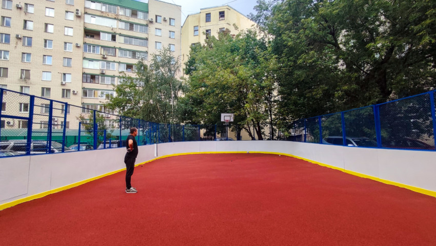 Широкий ракурс спортивной площадки во дворе с баскетбольным щитом и деревьями