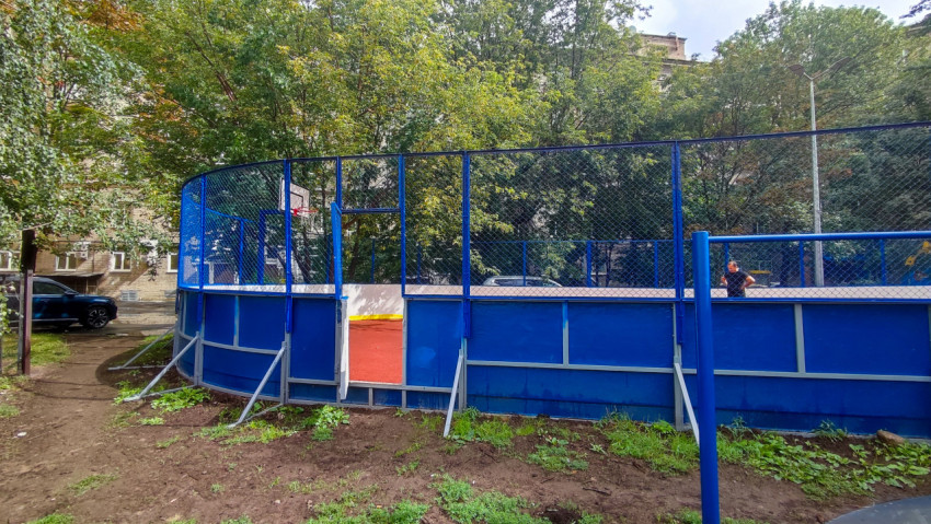 Синее ограждение спортивной площадки с подпорками на дворовой территории