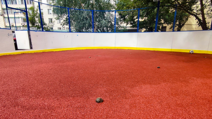 Камень на резиновом покрытии уличной хоккейной коробки