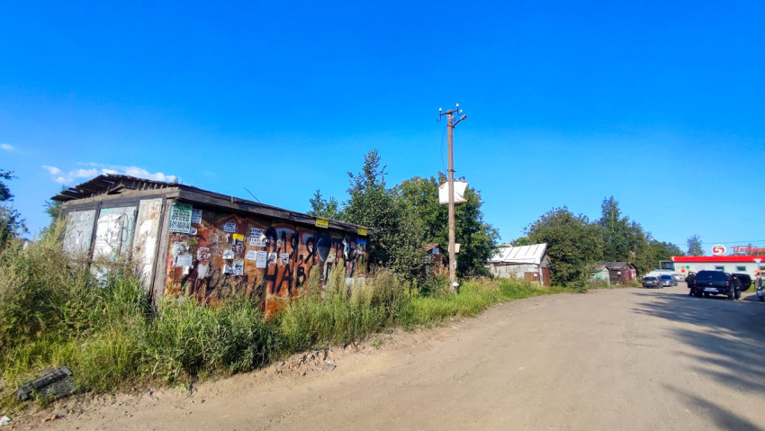 Грунтовая дорога у ржавого гаража с объявлениями и граффити