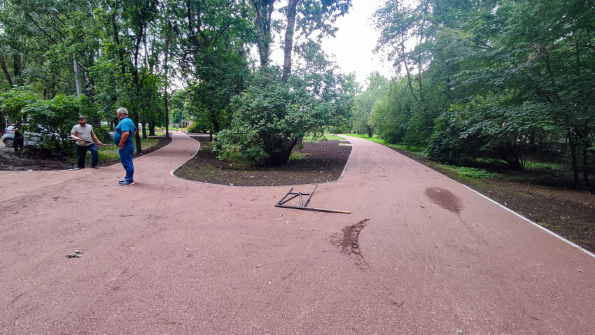 Рабочие разравнивают минеральную отсыпку на пешеходной дорожке в парке