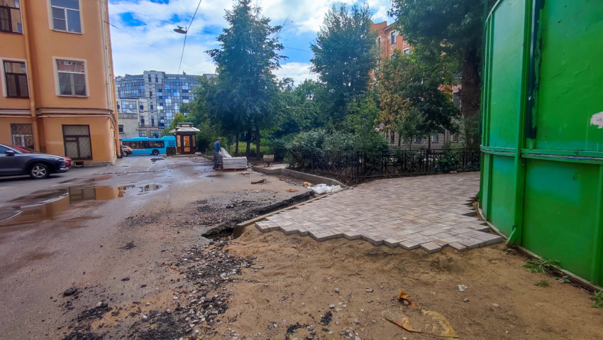 Участок ремонта двора рядом с ограждением спортивной площадки и новой плиткой