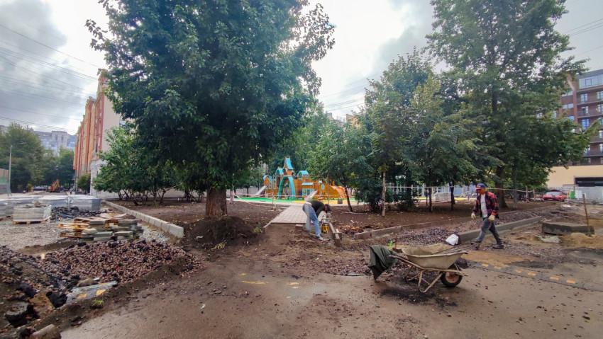 Рабочие укладывают бордюр и готовят основание рядом с детской площадкой