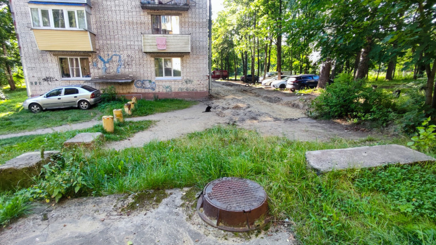Двор жилого дома с люком колодца и разрытым проездом перед началом коммунального ремонта
