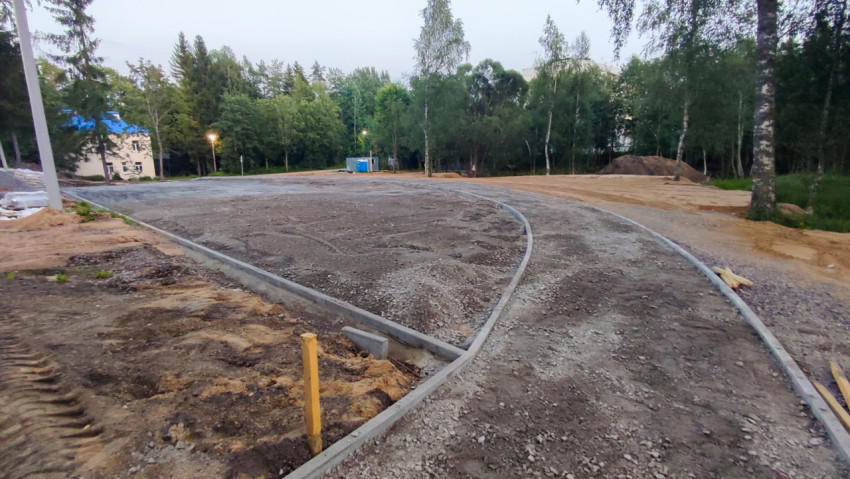 Основание из щебня и установленные бордюры на строящейся площадке у леса