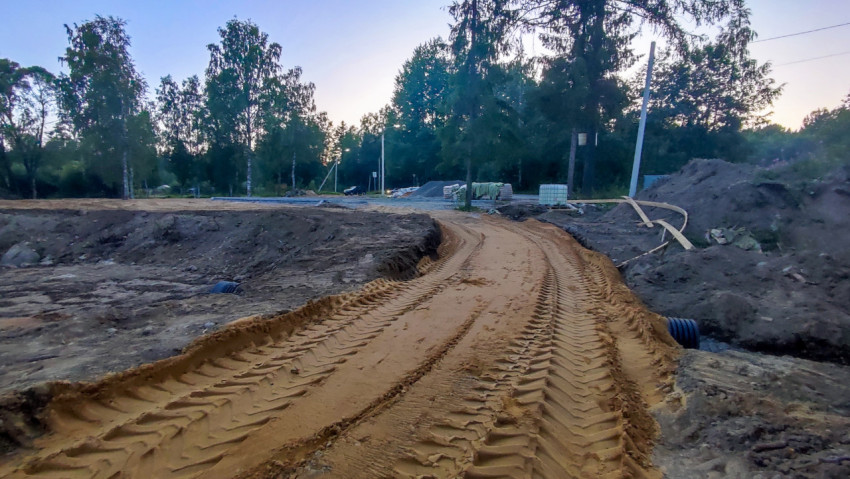 Временная песчаная дорога со следами гусениц и траншеями на строительной площадке