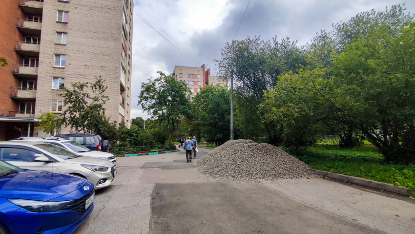 Куча щебня на дворовой дороге рядом с парковкой и жилыми домами