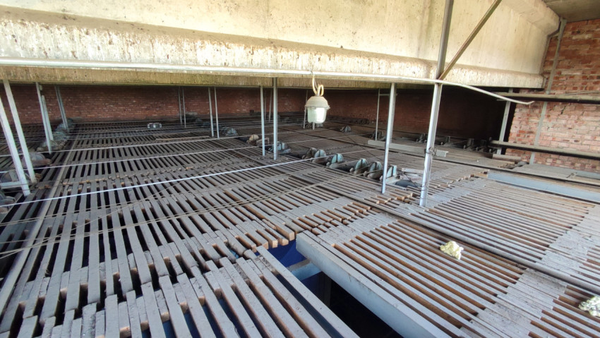 Техническое помещение с решетчатым металлическим настилом, кабелями и опорами на стадии ремонта здания