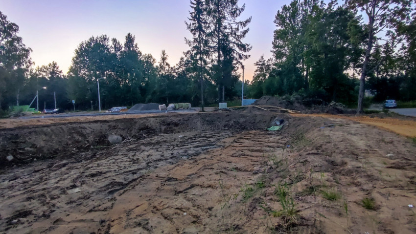 Выемка грунта и широкий котлован на строительной площадке у лесополосы
