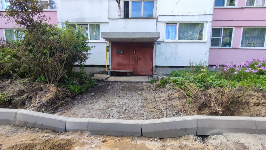 Фасад дома с подъездом и разметкой под дорожку между кустами и установленным бордюром