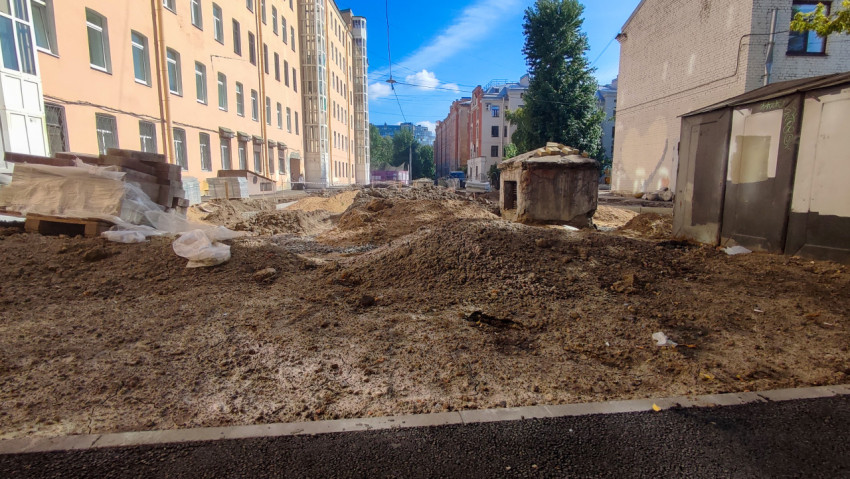 Кучи песка и щебня на дворовой стройке рядом с хозяйственными постройками