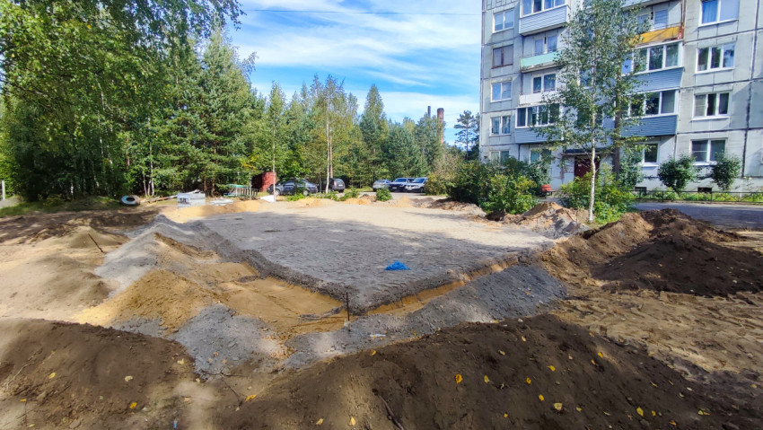 Подготовленная песчано-грунтовая площадка во дворе панельного дома с разметкой колышками