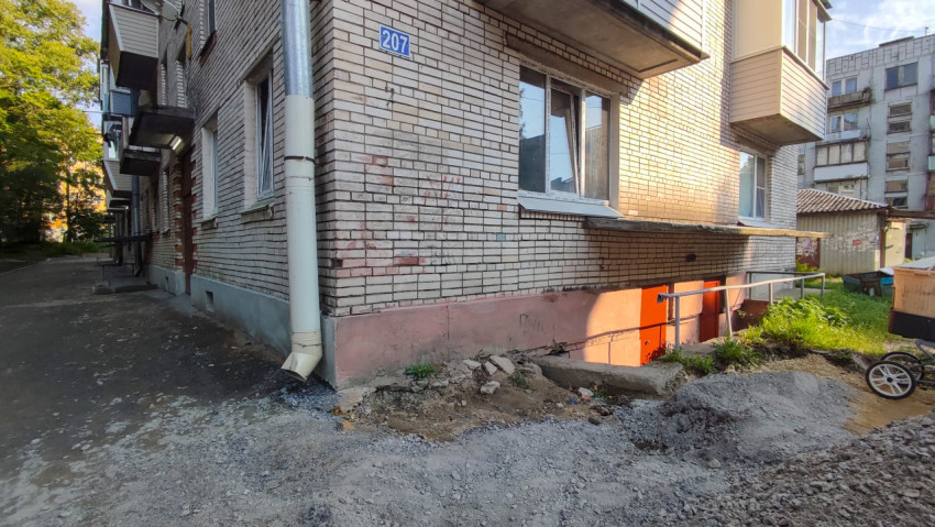 Угол жилого дома с номером на стене и раскопкой у цоколя