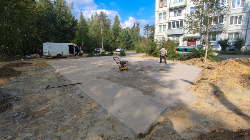Во дворе укладывают основание под проезд: песок разравнивают рядом с виброплитой