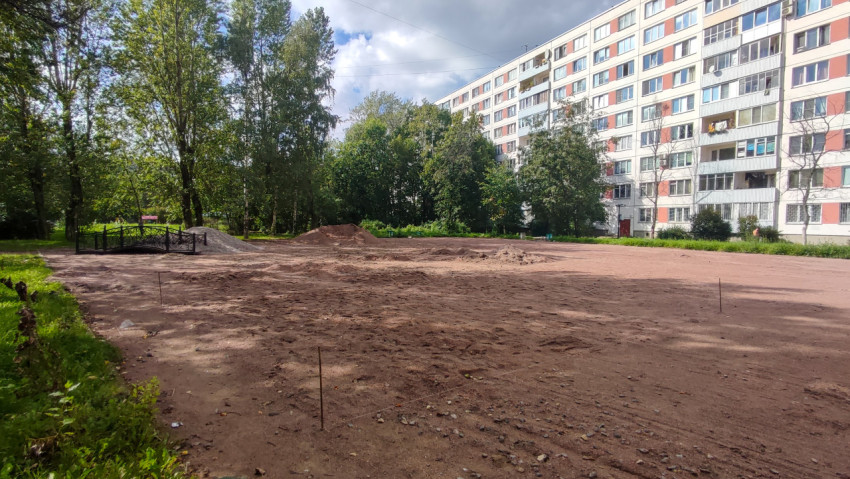 Большой раскопанный двор с кучами щебня и песка рядом с маленьким декоративным мостиком