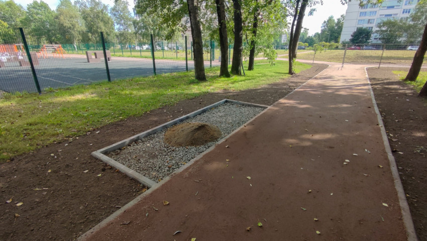 На парковой дорожке лежит куча песка на щебне, вокруг свежая земля после работ