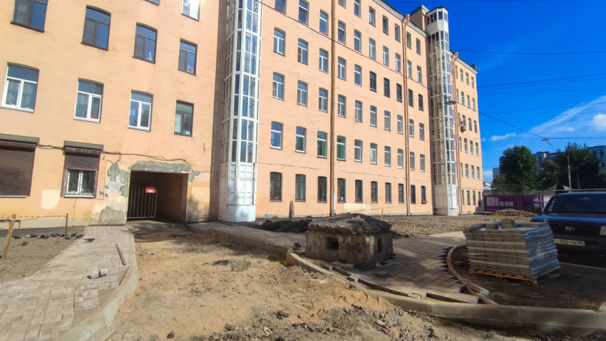 Фасад жилого дома и свежая тротуарная плитка на ремонтируемой придомовой территории