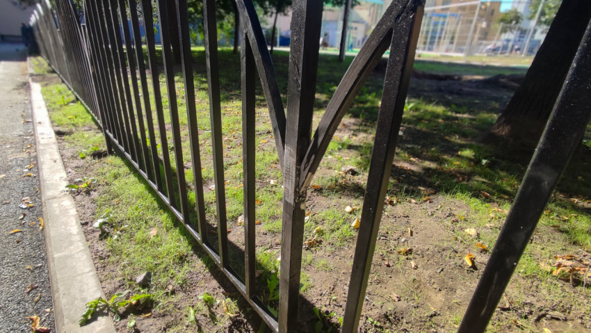 Погнутое металлическое ограждение у бордюра крупным планом