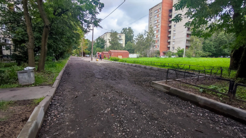 Щебёночное основание проезда и рабочий с виброплитой во время ремонта двора