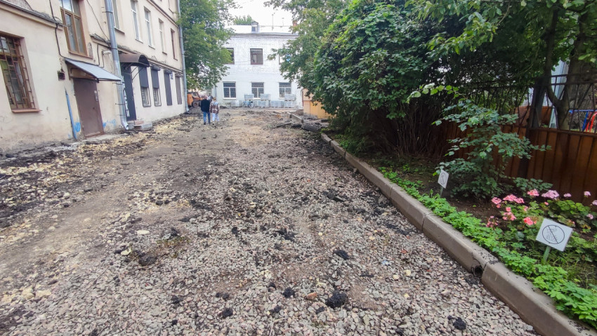 Дворовый проезд в ремонте со щебнем и бордюром между жилыми зданиями