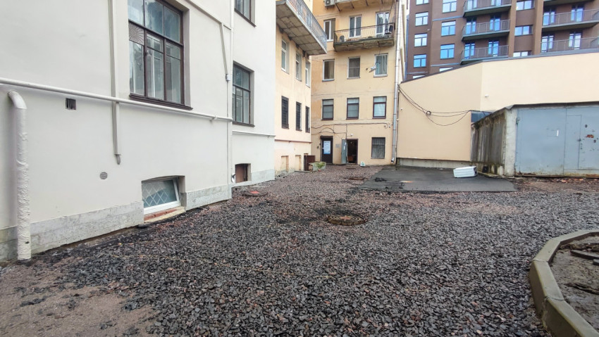 Гравийная дворовая проезжая часть с люком и фасадами многоквартирных домов