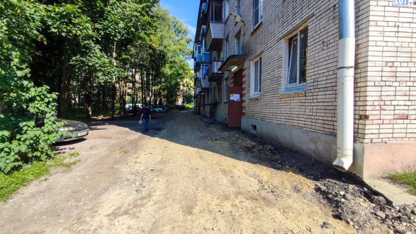 Демонтированное асфальтовое покрытие вдоль жилого дома перед восстановлением проезда