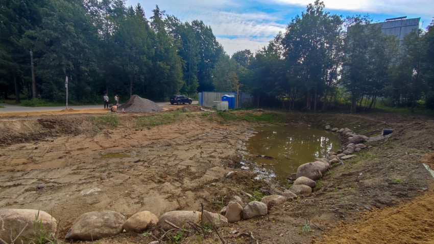 Земляные работы у водоёма с дренажной трубой и каменной отсыпкой