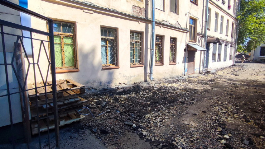 Ремонт фасада и цоколя здания с разобранным грунтом и строительным мусором у входа