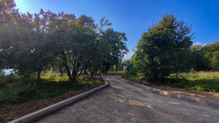 Новый проезд с бордюрами уходит в зелёную зону, пока вместо асфальта только уплотнённый щебень