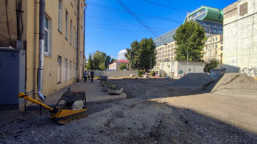 Виброплита и кучи щебня на площадке укладки тротуарной плитки