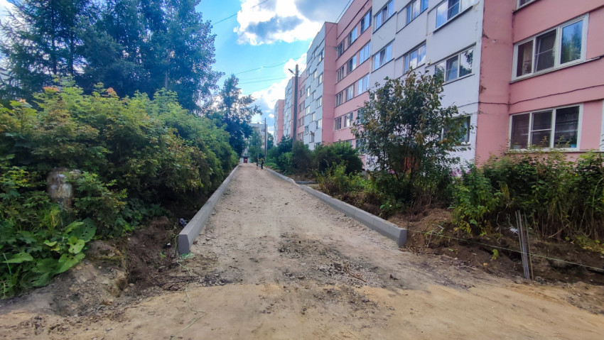 Дворовая дорожка вдоль жилого дома с установленными бордюрами и подготовленным основанием