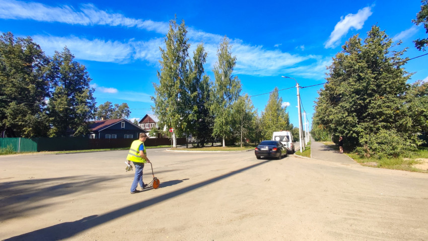 Замер проезжей части измерительным колесом на перекрёстке рядом со служебным транспортом