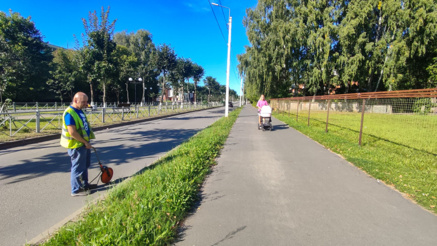 Рабочий с измерительным колесом делает замер у бордюра рядом с тротуаром
