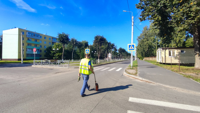 Рабочий идёт по «зебре» с мерным колесом, размечая участок перед проверкой покрытия рейкой