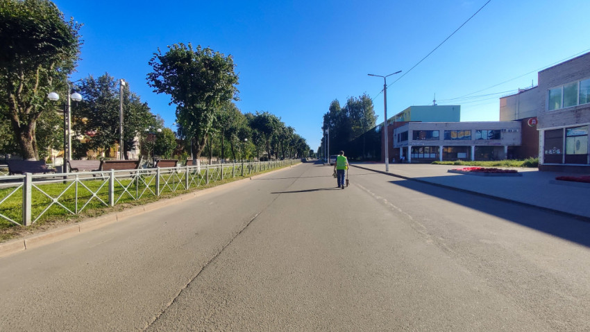 Замер расстояния измерительным колесом на улице возле здания и аллеи