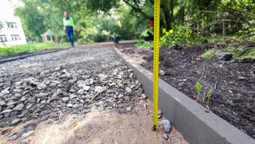 Измерение высоты бордюра и слоя подсыпки на строящейся дорожке со щебнем