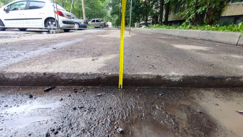 Измерение перепада высоты у края асфальтовой дороги рулеткой