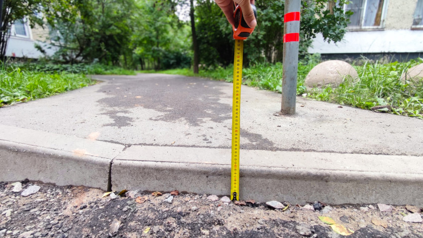 Измерение высоты бордюра рулеткой у пешеходной дорожки
