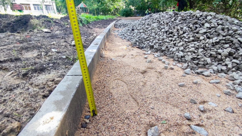Укладка песчаного основания и щебня вдоль бордюра на пешеходной дорожке