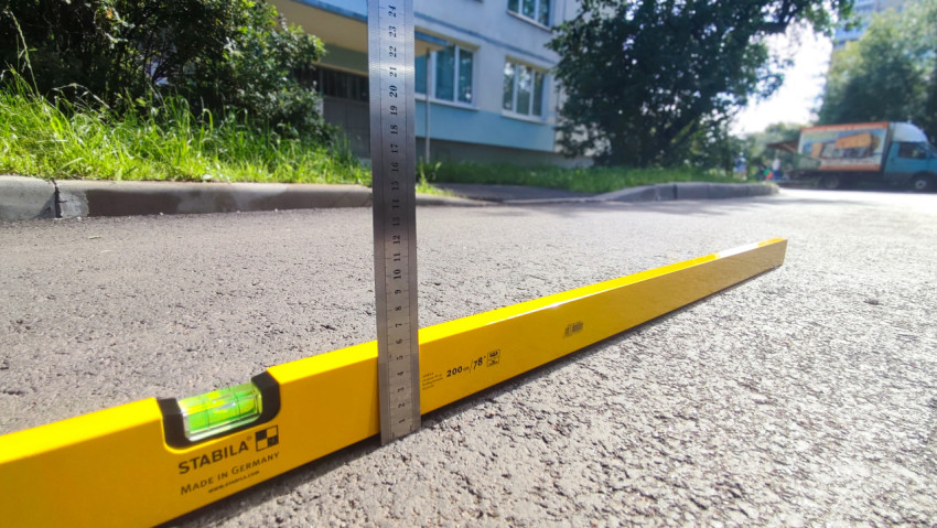 Измерение перепада высот на асфальте с помощью уровня и металлической линейки